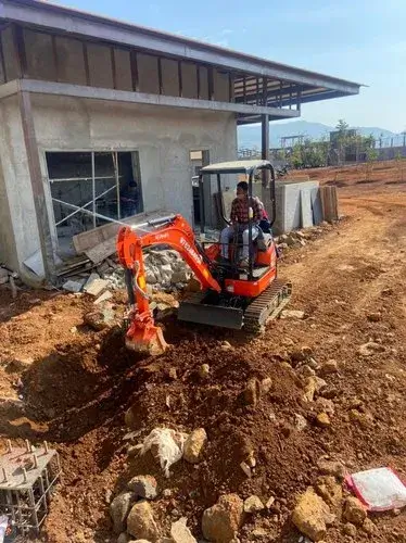 A compact excavator clearing rubble and dirt at a construction site for small excavations work with Earthworks Hawkes Bay.