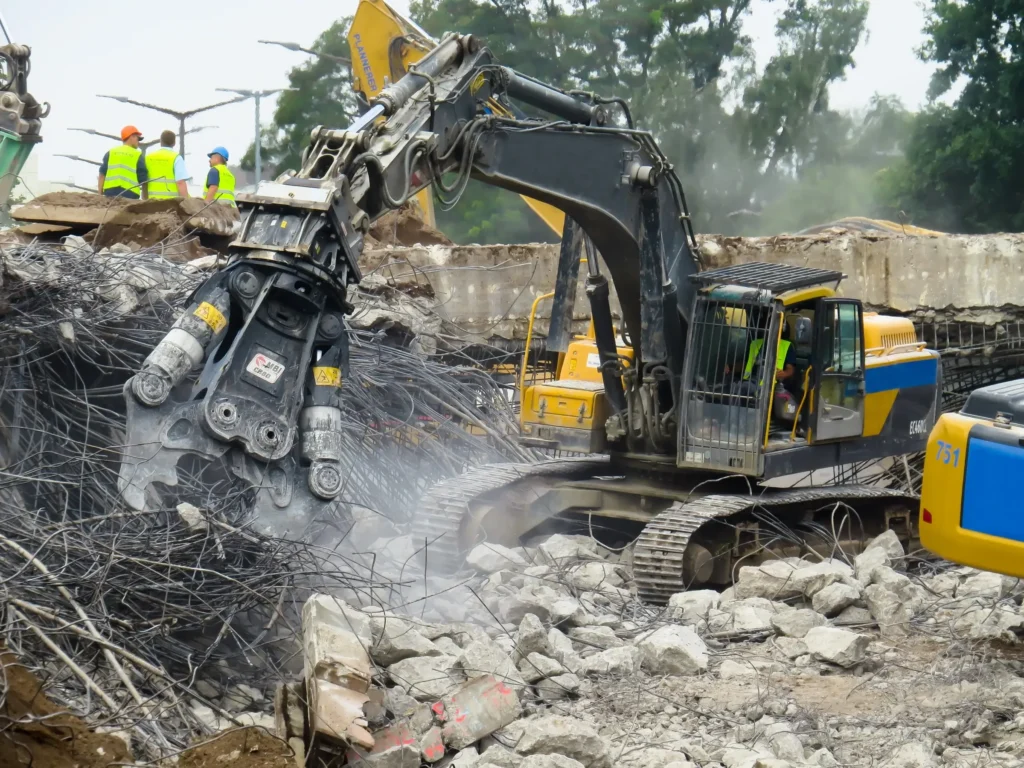 A construction team supervising an excavator during building demolition, reflecting Earthworks Hawkes Bay's expertise in Demolition Work.