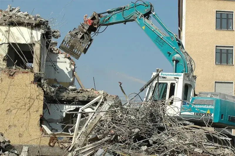 A demolition machine clawing through a reinforced concrete building, showing Earthworks Hawkes Bay's expertise in structural Demolition Work.