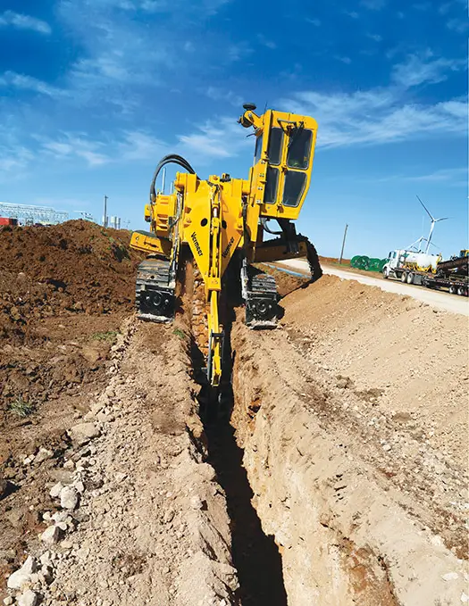 A heavy-duty trencher digging a precise trench along a roadside, showcasing Earthworks Hawkes Bay’s trenching service.