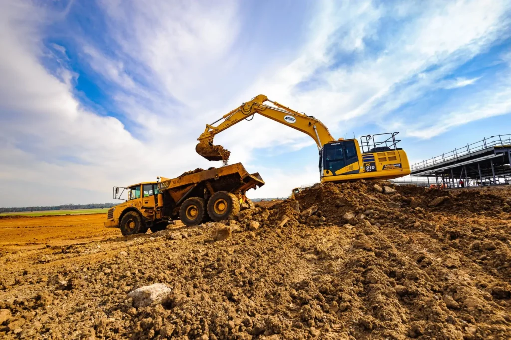 A large excavator transferring soil into a dump truck at a worksite, emphasizing Earthworks Hawkes Bay’s efficient earthmoving services. Learn more about our terms and conditions, privacy policy, careers, newsletter, and editorial guidelines to stay informed about our commitment to quality and service.