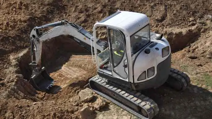 A mini excavator digging into the soil for a precise small excavations project by Earthworks Hawkes Bay.
