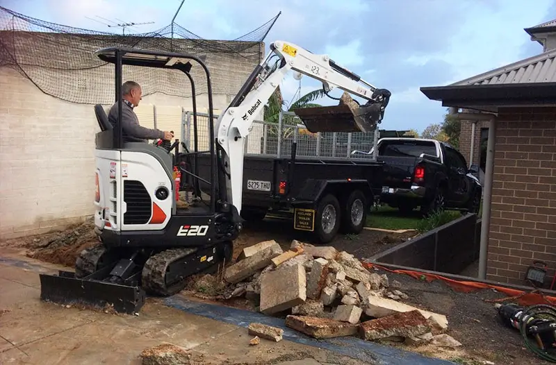 A mini excavator removing debris in a residential yard as part of a small excavations service by Earthworks Hawkes Bay.