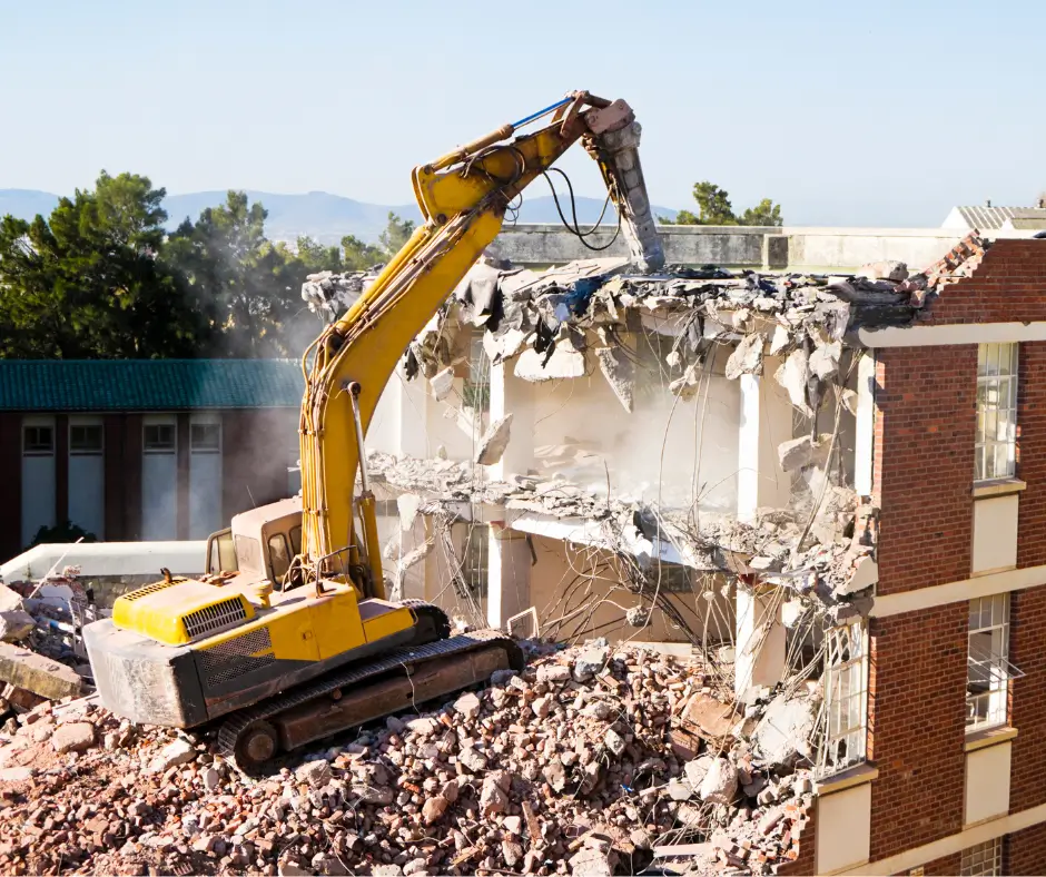 An excavator tearing down a multi-story building, illustrating Earthworks Hawkes Bay's large-scale Demolition Work capabilities.